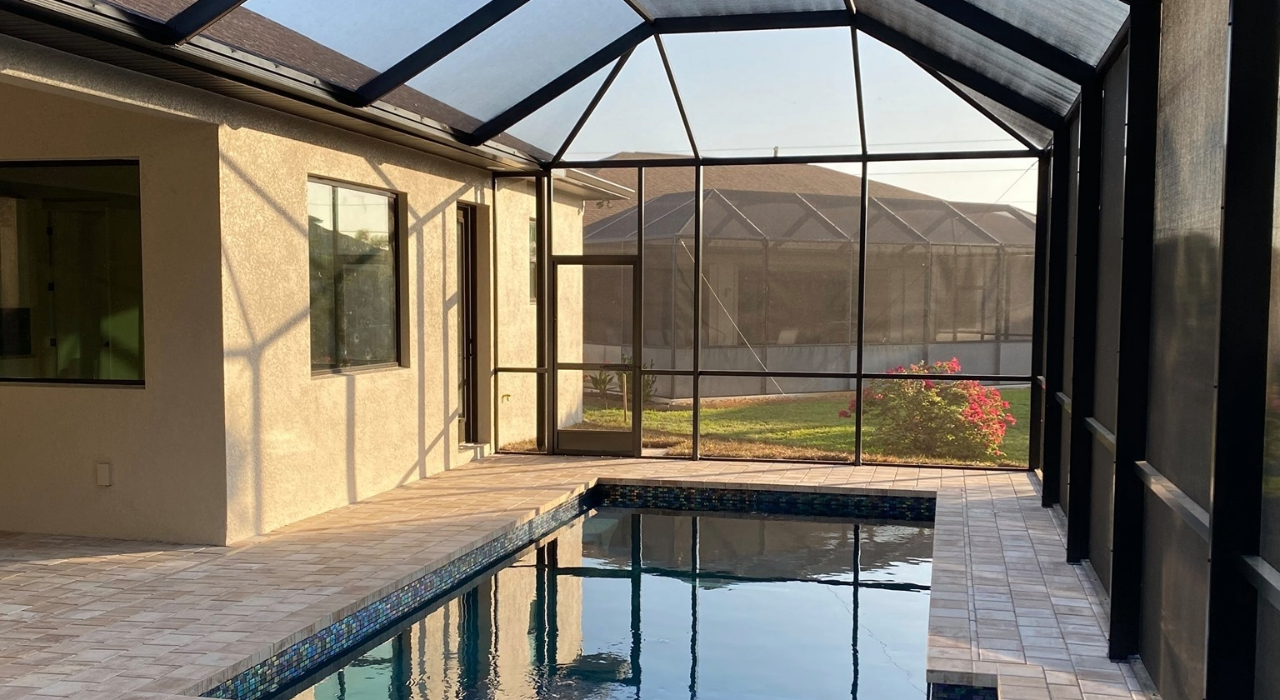 Comfortable outdoor seating next to a pool under a clean mesh dome, showing how to clean pool screen enclosure.