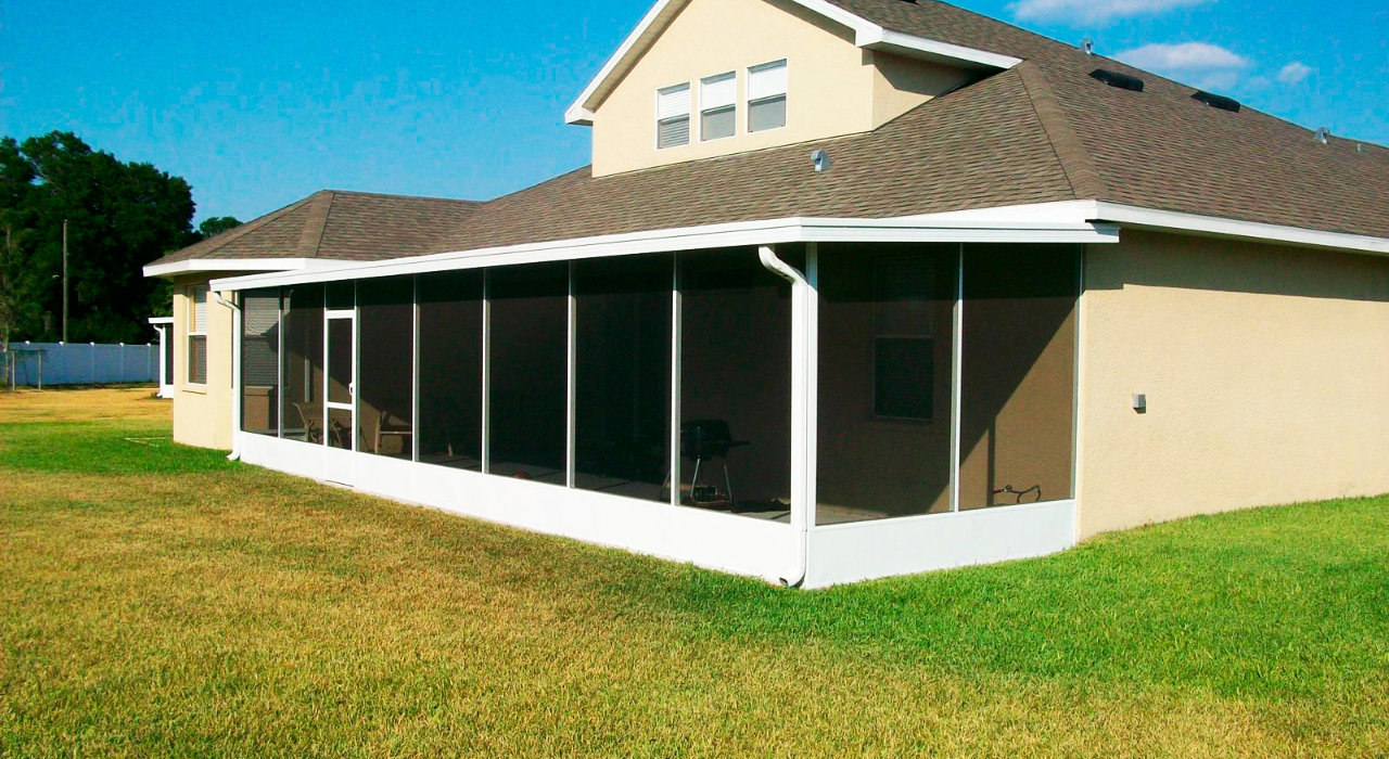 Looking out from a clean, bug-free pool enclosure toward a lush landscape, showing why do florida pools have cages.
