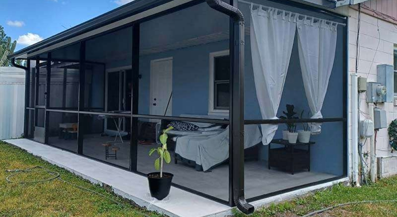 A screened patio structure featuring dark metal framing and interior white curtains, representing functional lanai enclosure ideas.