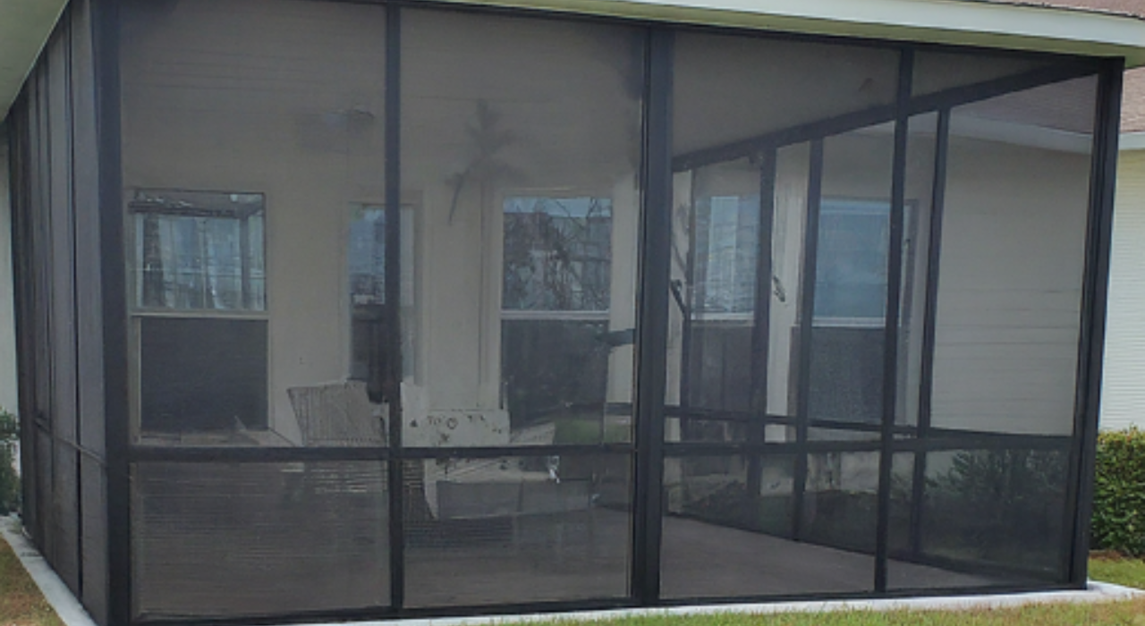 An exterior view of a custom screened room attached to a residential home, providing excellent lanai enclosure ideas.