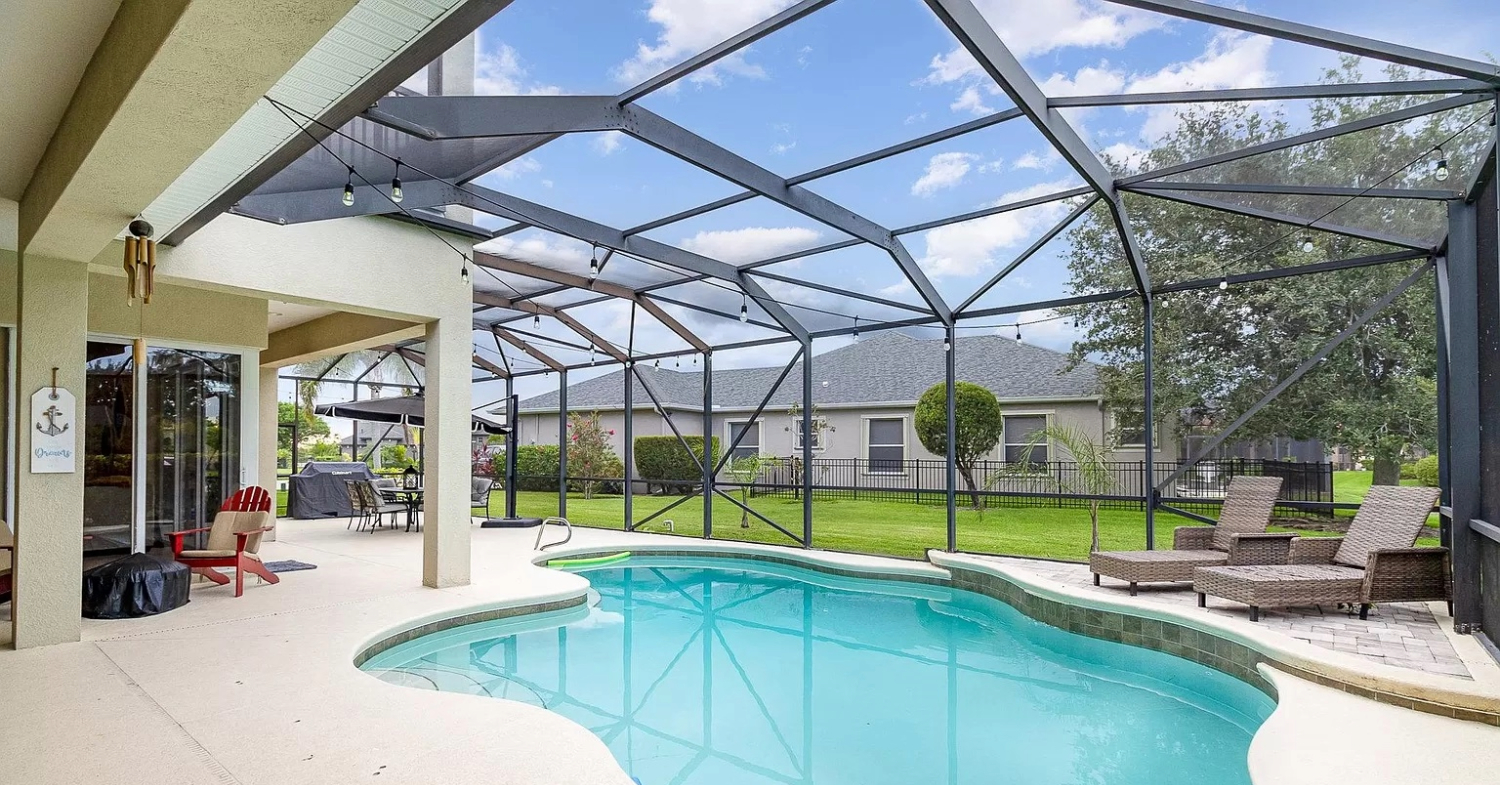 A spacious patio and freeform swimming pool showcasing large-span pool enclosure screen types.