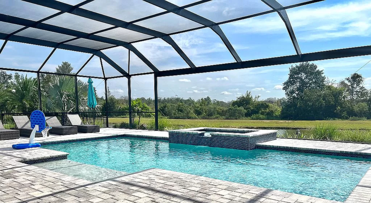 A large backyard swimming pool and spa protected by a dark metal frame, demonstrating different privacy screen options for pool enclosure.