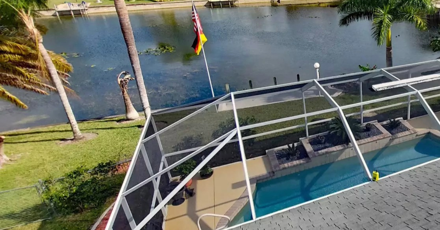 An aerial view of a white-framed backyard structure near a canal, highlighting effective privacy screen options for pool enclosure.