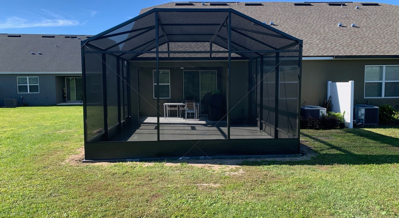 A dark metal patio enclosure illustrating the functional differences of screen room vs sunroom.