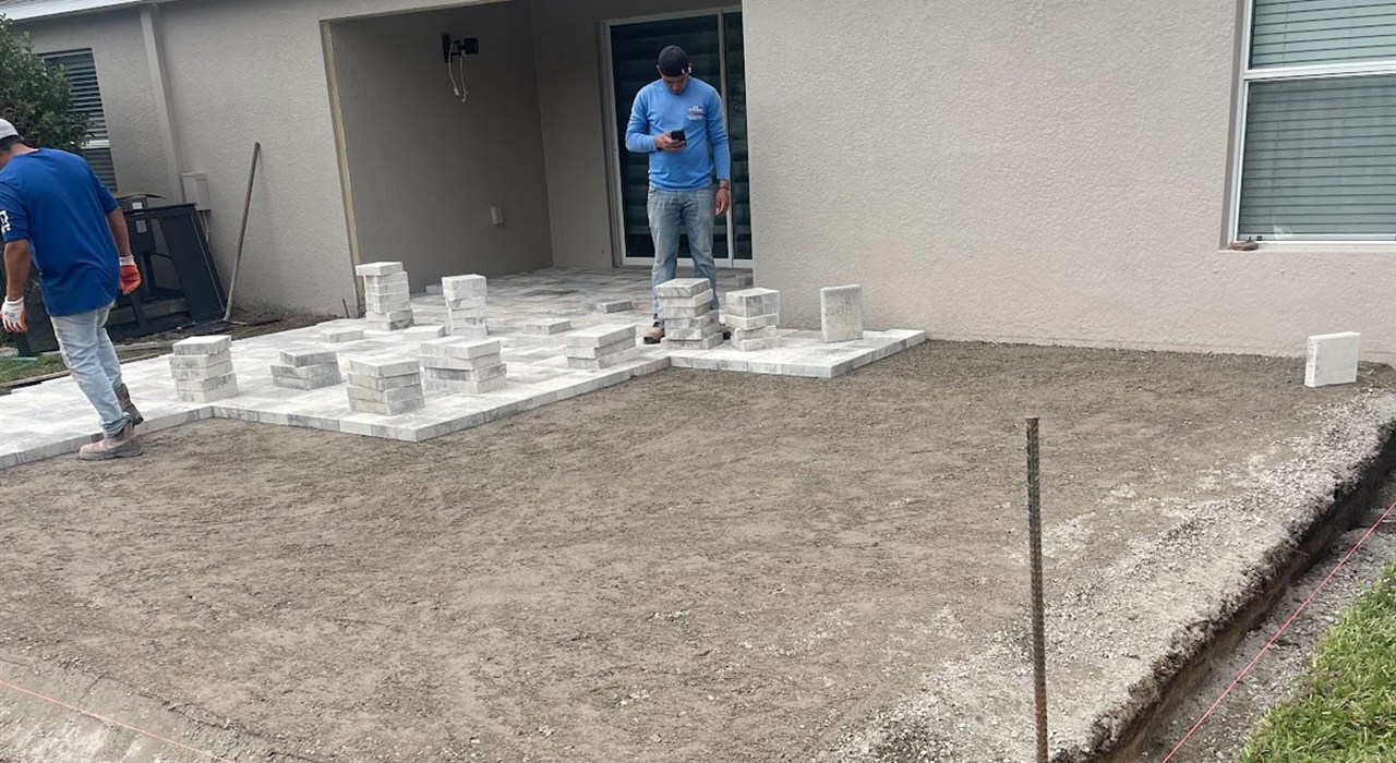 Contractors laying light grey stones to select the paver color for your Tampa patio.