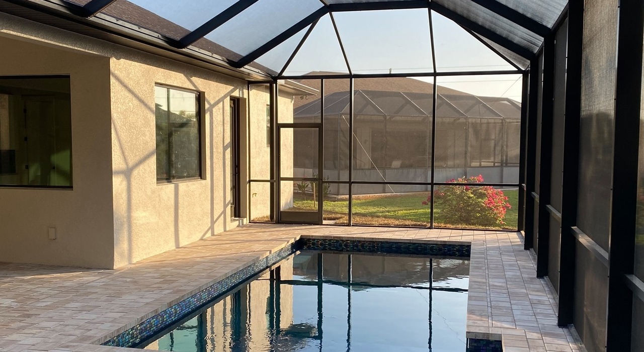Interior view of a backyard pool cage vs pool screen enclosure protecting the water.
